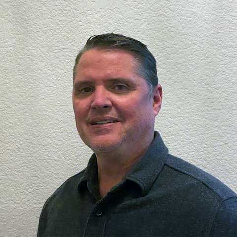 A professional man standing against a neutral wall, representing expertise in blockchain technology.