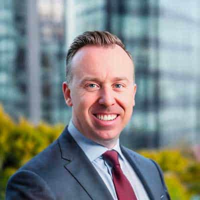 Professional businessman in suit smiling outdoors, modern city background with blockchain technology theme.